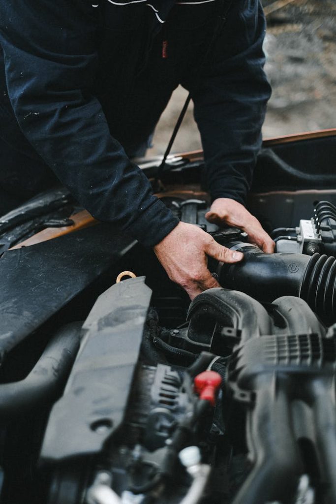 pexels-photo-4315571 Close-up of a mechanic's hands working on a car engine inside a workshop.