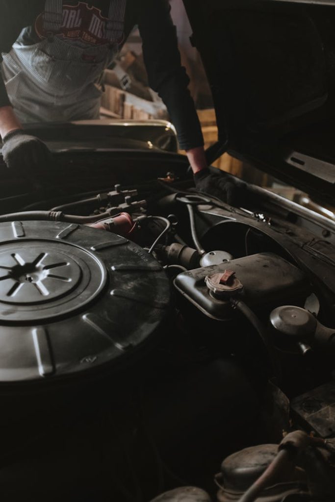 pexels-photo-4489765 Close-up of a mechanic repairing a car engine in a garage setting.