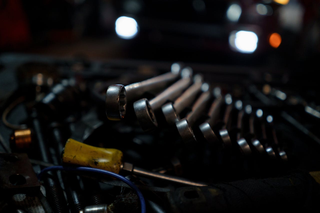 A detailed shot of various tools arranged with focus on wrenches in a garage environment.